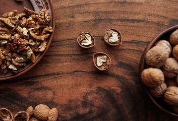shelled walnuts and walnuts in a bowl on a wooden background.