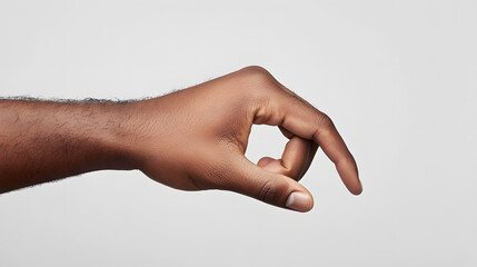 Close-up of a dark-skinned male hand reaching out, fingers slightly curved as if grasping or picking up something small. The arm is extended against a plain white background.