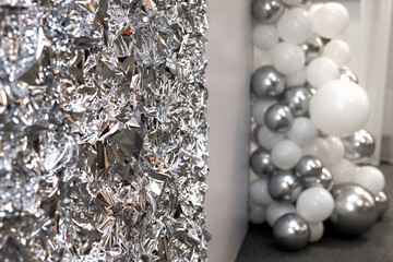 A photo zone made of pressed foil or silver-colored polysilk with balloons.
