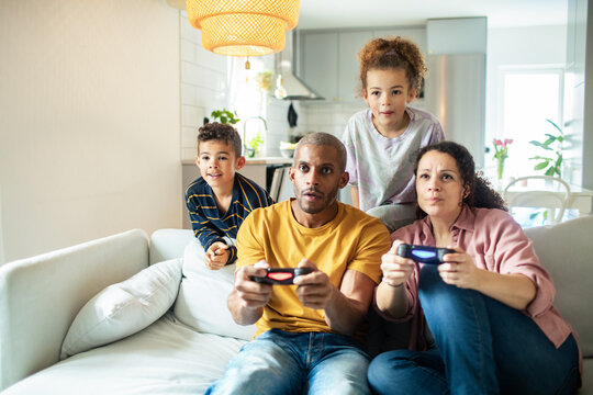 Biracial family playing video games together at home in living room