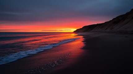 Fototapeta premium A stunning sunset over the ocean reflecting fiery colors on the beach