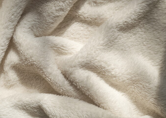  Beige soft eco-fur textile and textured pleats in sunlight, beautiful shadows