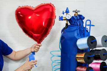 A female aerodesigner puts on a red foil heart using helium from a balloon.