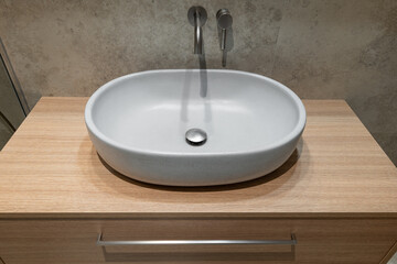Minimalist bathroom sink with a sleek white basin on a wooden countertop and wall-mounted faucet