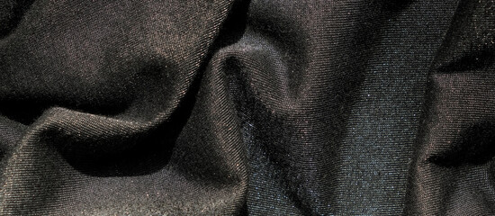 Black fabric with soft folds and slight shining effect. Close-up texture, abstract background....