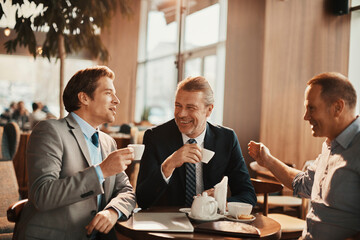 Businessmen having serious conversation over coffee in modern cafe