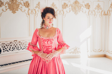 Elegant woman in a vintage pink dress in a grand historic room