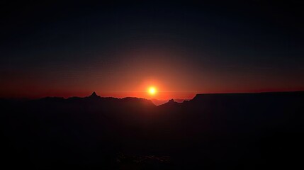 Fototapeta premium Sunset over mountains silhouetted against a dark evening sky