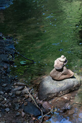 Stacked stones by a forest stream in sunlight
