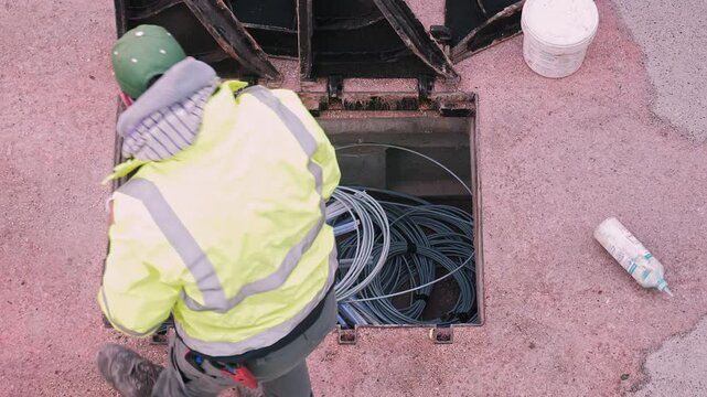 Installation of underground fiber optic network. Cables coiled inside an open access point during wiring work for high-speed internet infrastructure.