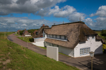 Reet gedeckte Häuser am Deich von Nordstrand