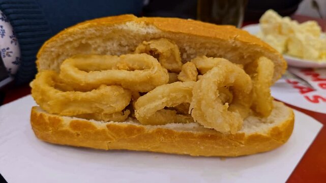 Close-up of a classic Spanish calamari sandwich, known as bocata de calamares, served in a crusty baguette in Madrid.