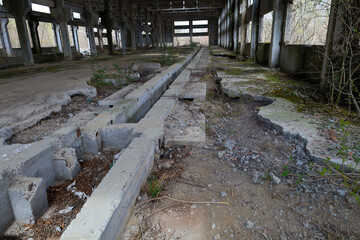 Interior of a large abandoned concrete building with a destroyed floor and walls with numerous...