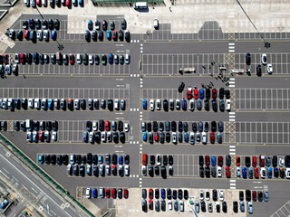 Aerial view of new cars stock at factory parking lot. Above view cars parked in a row. Automotive industry. Logistics business. Import or export new cars at warehouse. Big parking lot at port terminal
