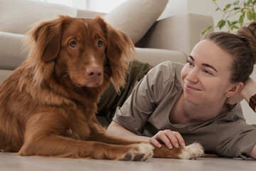 young woman with her dog laying on floor at home