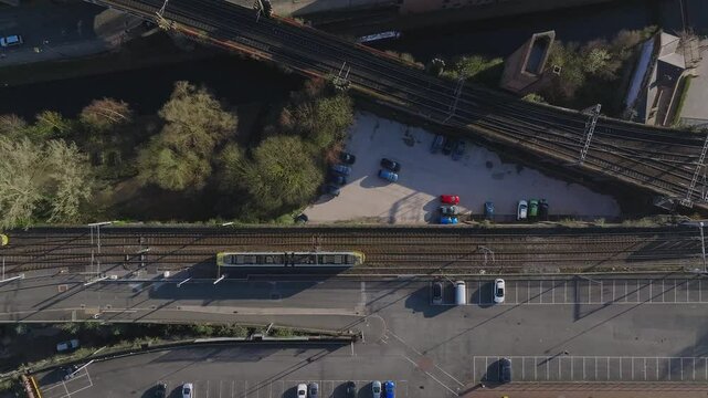 Aerial shot of Manchester, UK, showing railway tracks, a road, a parking lot, trees, and a waterway with gradual panning or tracking motion.
