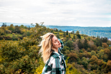 Woman closing eyes and relaxing in the wind on a hilltop in autumn in Stuttgart