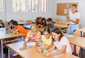 Schoolchildren use mobile phones at the lesson in the classroom