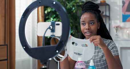 The woman collaborates with a skincare brand, recording a product review. She shows a facial sheet...