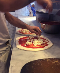 Pizzero haciendo una pizza en la cocina de una pizzería