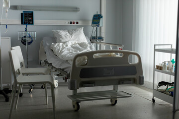 An empty hospital room featuring a bed along with various essential medical equipment and supplies