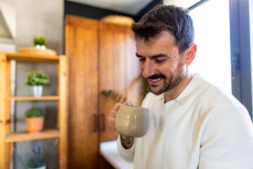 Happy man enjoying a cup of coffee in a modern kitchen, starting his day with a warm beverage