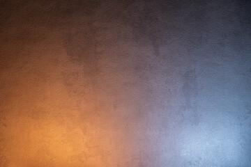 Texture of gray concrete wall with gradient lighting in warm and cold tones.