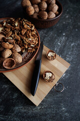 walnuts in a plate on a wooden board.shelled nuts and a knife