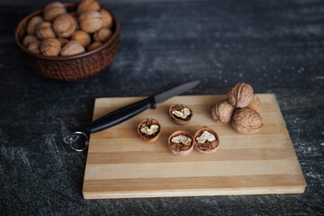 whole and shelled walnuts on a wooden board with a knife and a bowl