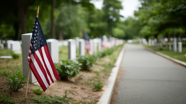 American flag gently flutters beside white headstones in a military cemetery, honoring fallen heroes on Memorial Day with peaceful surroundings - Powered by Adobe