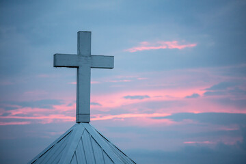 Cross on chapel against pink and blue sky at sunset