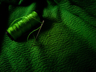 green thread spool lies on a green textured fabric