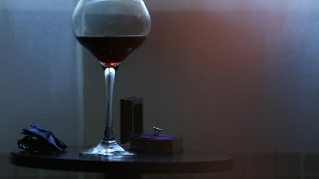 A pair of cufflinks are displayed in a black box with a purple velvet base. The cufflinks are silver with a clear stone.