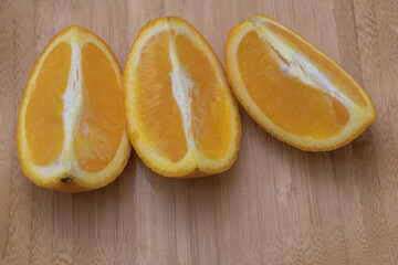 Two orange halves cut in half, one with the inside facing up and the other facing down, on a light...