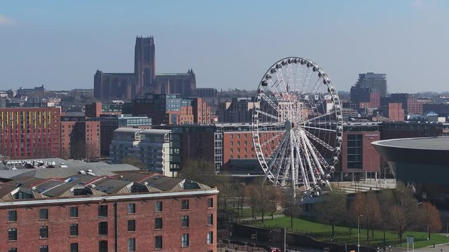 Aerial view of Liverpool with a slow pan showcasing the Liverpool Cathedral, Wheel of Liverpool, MandS Bank Arena, streets, and surrounding greenery.