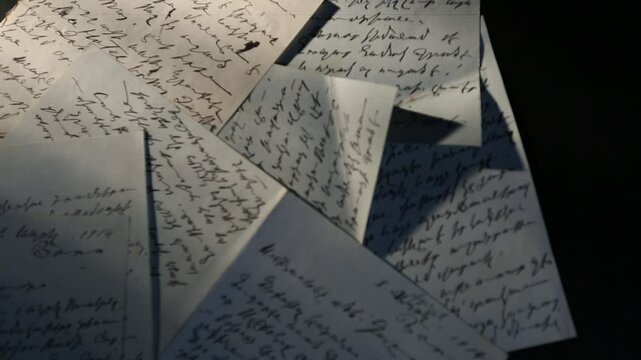 This video shows a collection of handwritten letters scattered on a dark surface. The elegant script and vintage paper evoke a sense of history and personal communication.