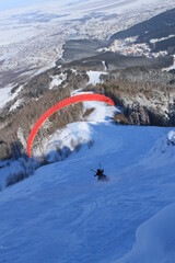  skier is descending a snowy slope with a red line indicating their path.