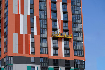 Worker is engaged in external works, insulation of house, renovation paints building, standing on...