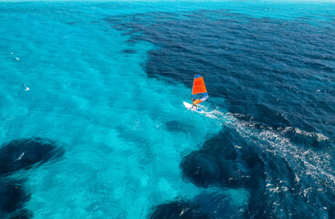 Aerial view of windsurfer on blue sea at sunny summer day. Windsurfing. Extreme sport and vacation....