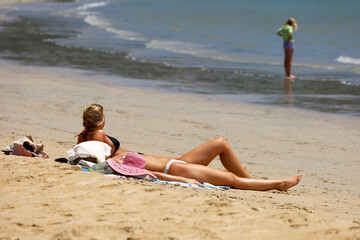 Fototapeta premium Two girls in bikini lying on a sand and tanning on sea beach