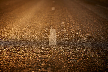 Asphalt road and marking lines at sunset, close-up