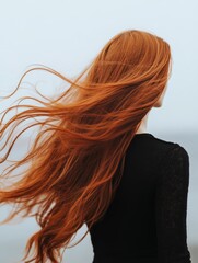 Obraz premium Woman with vibrant red hair flowing in the wind