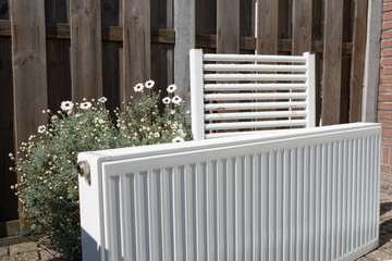 Used heating radiators stacked in a courtyard after removal, ready for recycling or disposal. Highlights renovation process and metal waste management.