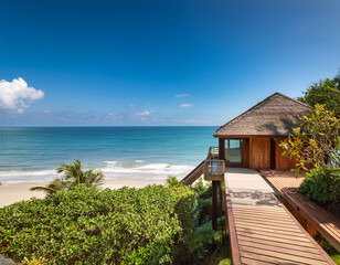 luxury accommodation offers breathtaking ocean views a serene wooden cabin nestled in lush greenery leading to a tranquil beach under a clear sky