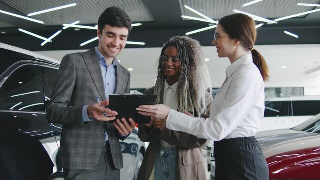 Professional car dealership interaction with customers discussing purchase options at an upscale showroom in the afternoon light