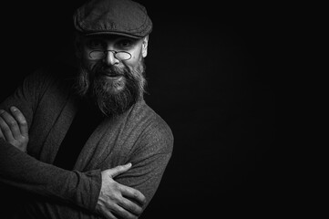 Black and white, portrait of an emotional bearded man in a gray hat, gray sweater and glasses...