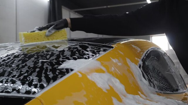 Washing sports car with sponge and soap to ensure a shiny, spotless exterior. Ideal auto detailing and car care 4k video.