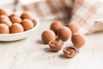 Chocolate truffles with cocoa powder and caramel filling on kitchen table.