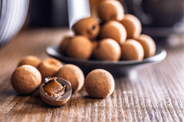 Chocolate truffles with cocoa powder and caramel filling on wooden table.
