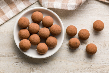 Chocolate truffles with cocoa powder in bowl on kitchen table. Top view.